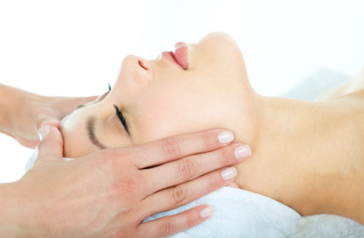 Photo of masseuses hands doing relaxing massage on young woman's face