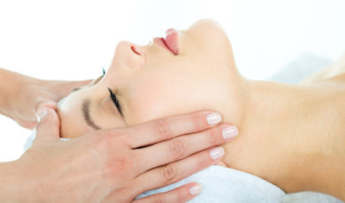 Photo of masseuses hands doing relaxing massage on young woman's face